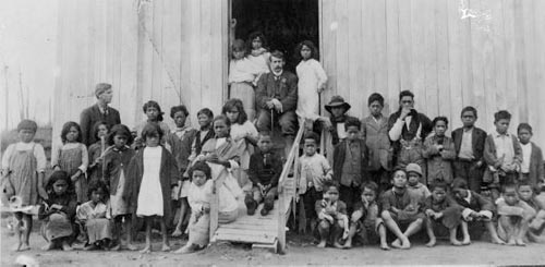 A photograph of John Laughton seated with a group of Maori children