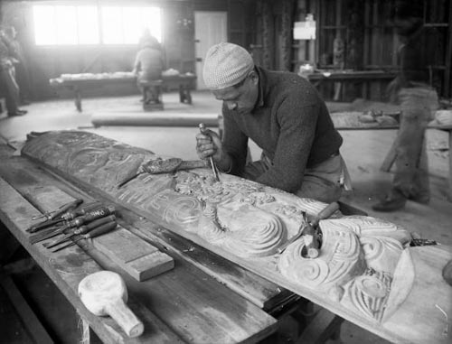 Pineāmine Taiapa working on a wood carving with a chisel