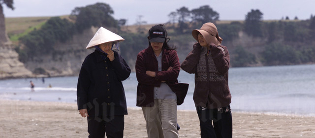 Vietnamese women stroll on an Auckland beach
