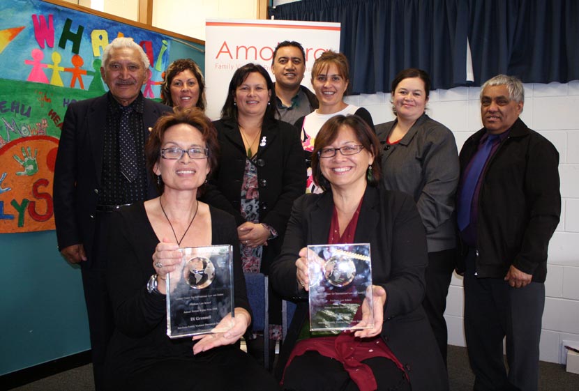 Group of people smiling and holding framed awards.
