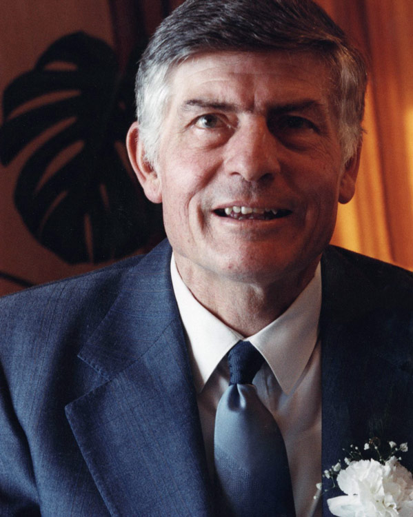 A colour head and shoulders photograph of Colin Murdoch wearing a suit and tie