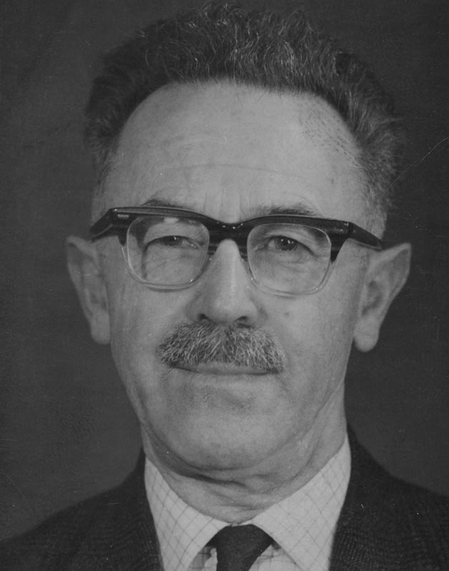 A head and shoulders portrait of Fergus Sheppard in middle age, wearing plastic-framed glasses and a moustache.