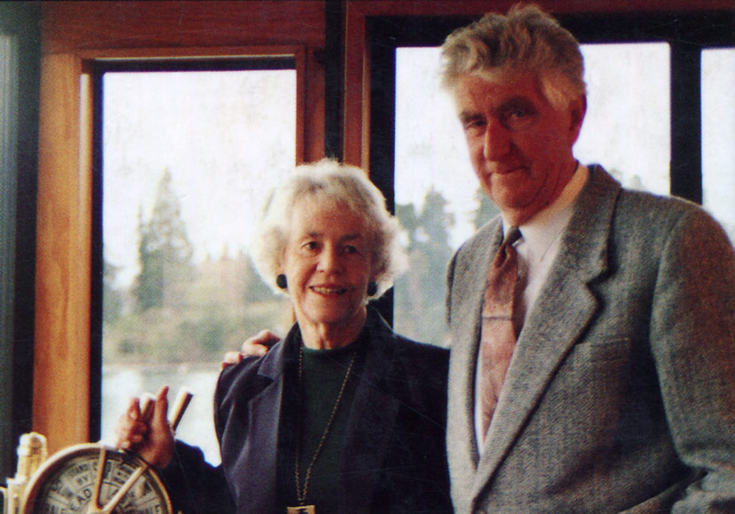 Olive and Les Hutchins in later life, smartly dressed, framed by the windows of Earnslaw’s cabin. Olive has her hand on the ship’s telegraph.