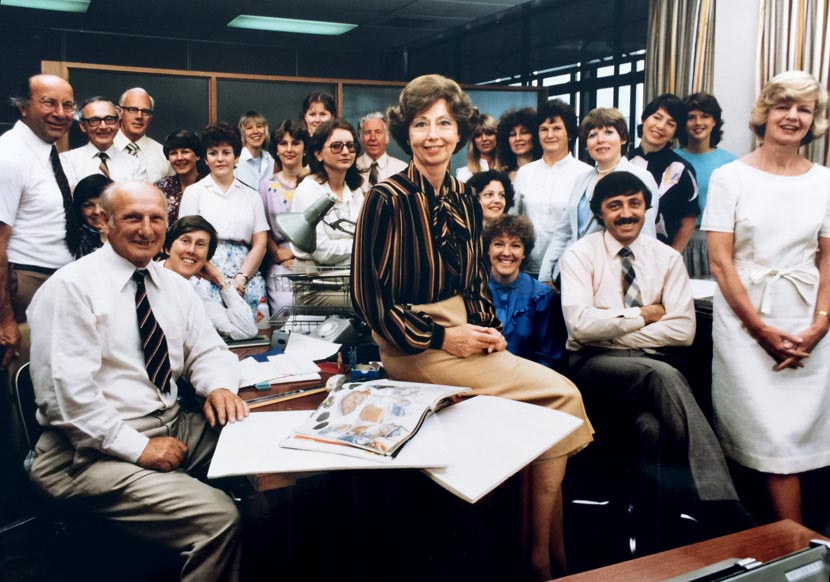 A group photograph showing 24 people in an office. 
