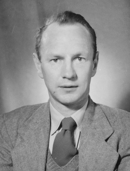 A head and shoulders studio portrait of Bill Pearson wearing a suit and tie. 