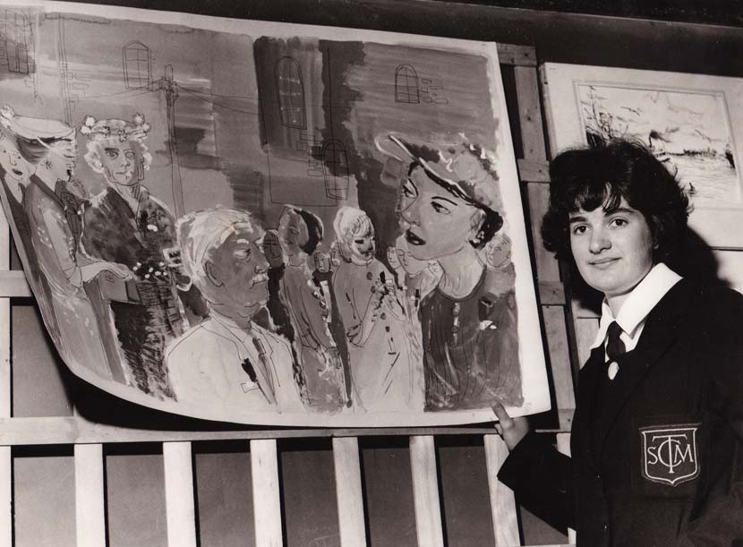 A teenage Pauline Thompson, in a school uniform with SMTC monogrammed on the blazer, stands beside a large painting depicting a group of people in front of some buildings.
