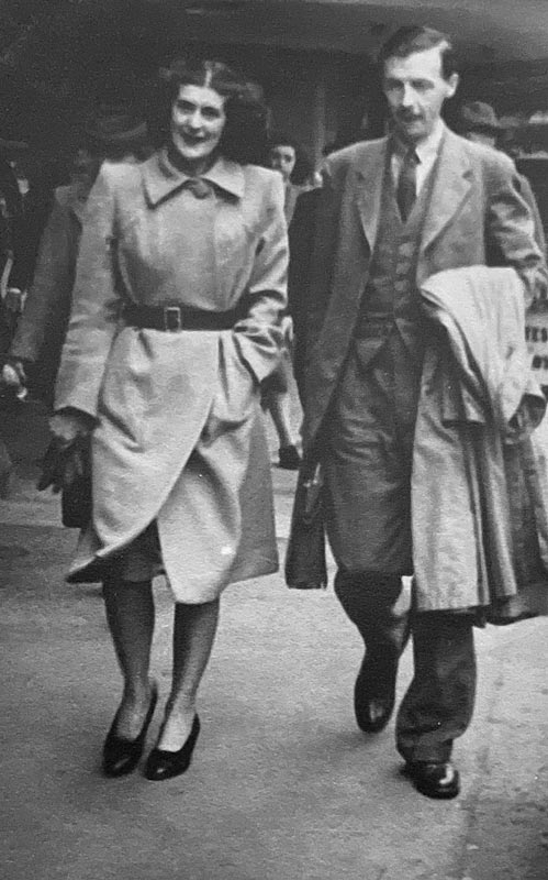 A candid snapshot of Molly and Michael Joseph walking down a city street, formally dressed.