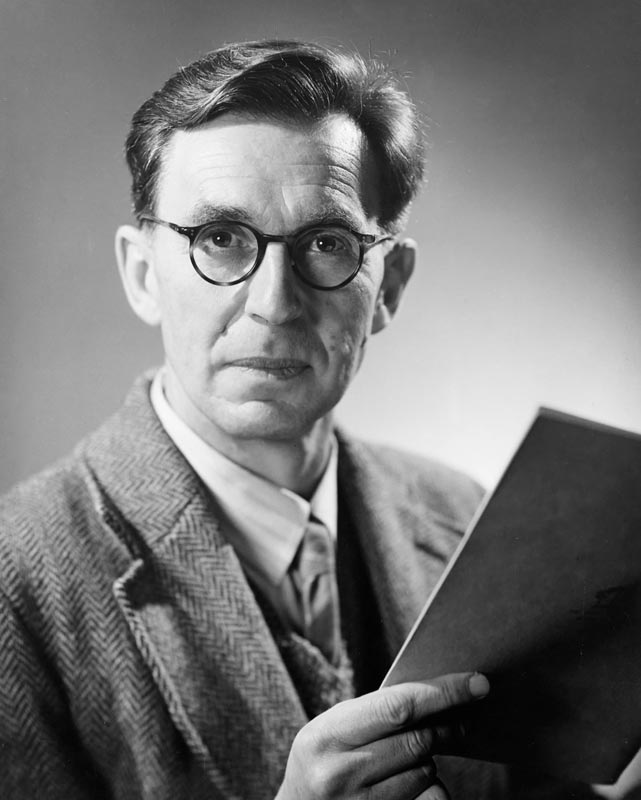Man wearing glasses and suit holding book.