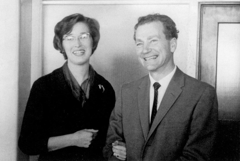 A young couple standing arm in arm, smiling.