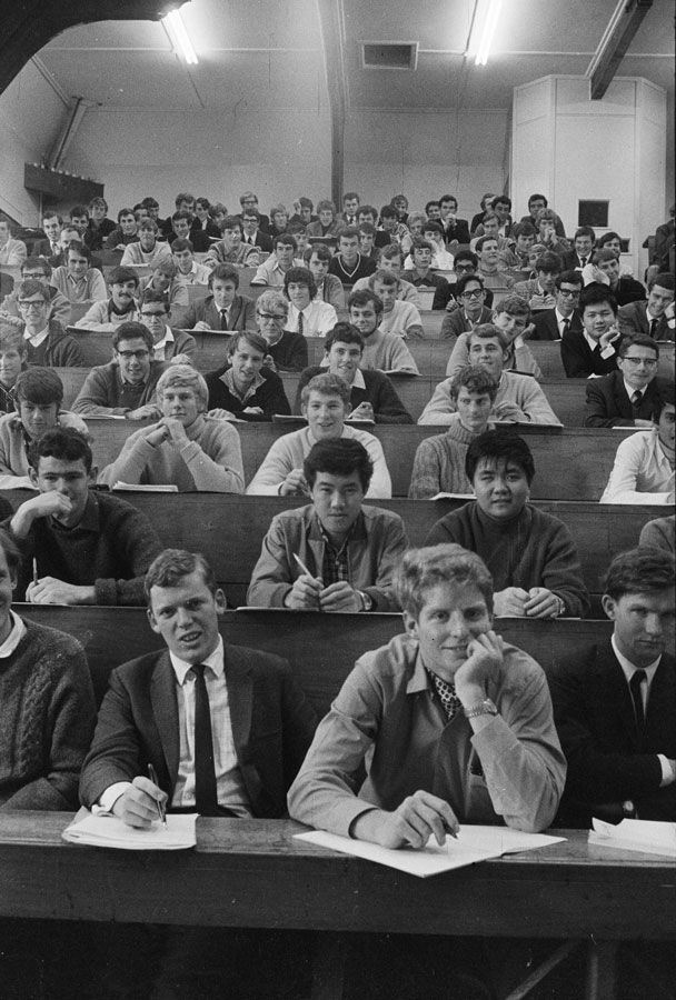 A roomful of university students sitting in tiered seats in a lecture theatre.