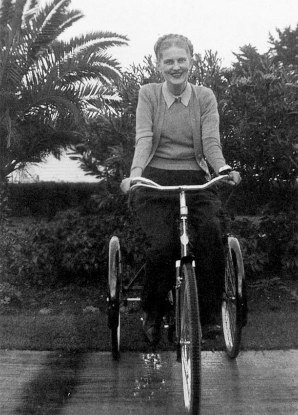 A smiling woman sitting on a tricycle.