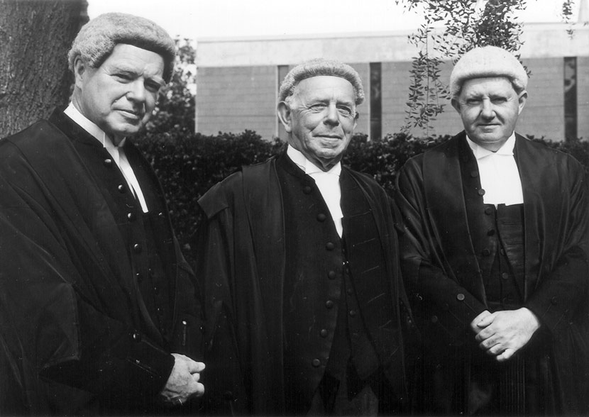 Three judges, in wigs and gowns, standing outdoors.