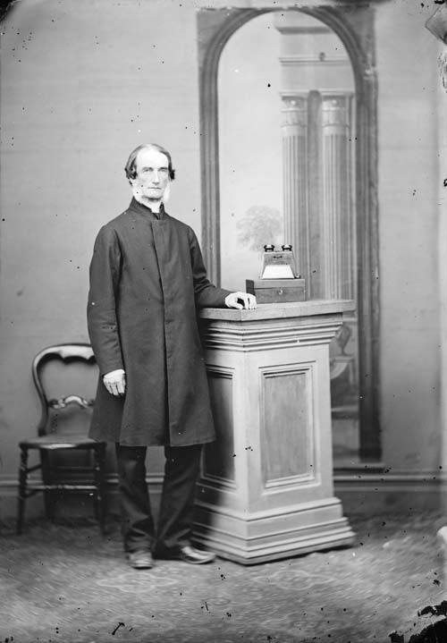 A photograph of Octavius Hadfield standing and wearing clerical clothing