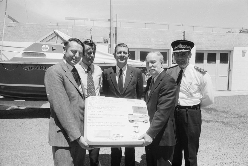 Five men, one in a police uniform, holding a box. 
