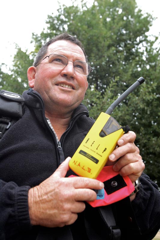 Man holding a yellow personal locator beacon.