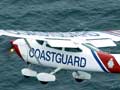 A small plane labelled ‘Coastguard’ flies above a rescue boat and an overturned boat in the sea 