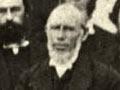 A photograph of John Inglis standing in front of a table when other men behind him