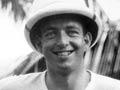 A photograph of Emmet McHardy wearing a pith helmet in an outdoor tropical setting