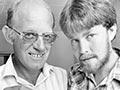 Don Merton and a bearded younger man pose indoors with a bird’s nest. Merton holds a small feeding scoop. 