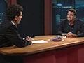 Photograph of Paul Holmes and Dennis Conner seated at a desk in the studio set of the Holmes show.