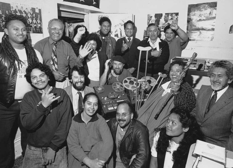 Large group of people crammed into a radio station smiling at the camera.