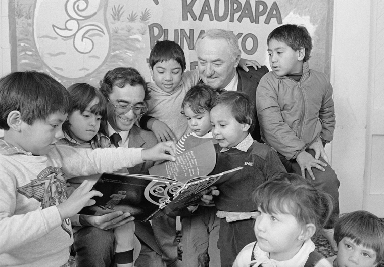 Sir Eddie Durie and Paul Temm reading a book to children.