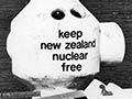 A photograph showing the look-out tower on the roof of Athfield’s house bearing the slogan ‘keep New Zealand nuclear free’, with an American warship in the harbour in the background
