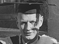 A photograph of Bill Pearson in a graduation gown and cap.