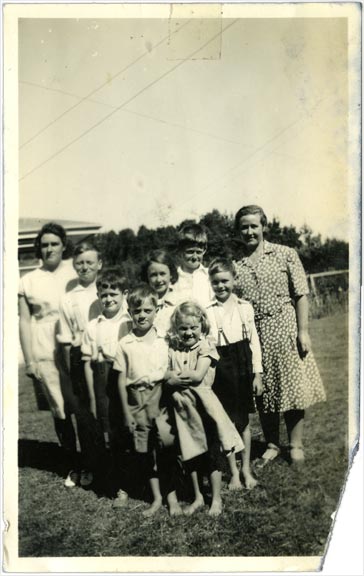 Seven school kids and two teachers posing for photograph in paddock