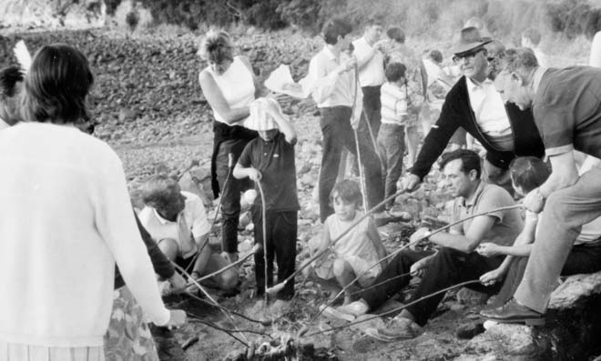 Cooking sausages over an open fire, Cable Bay, 1970