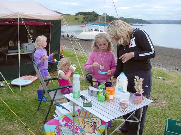 Family gathered around picnic table in front of tent
