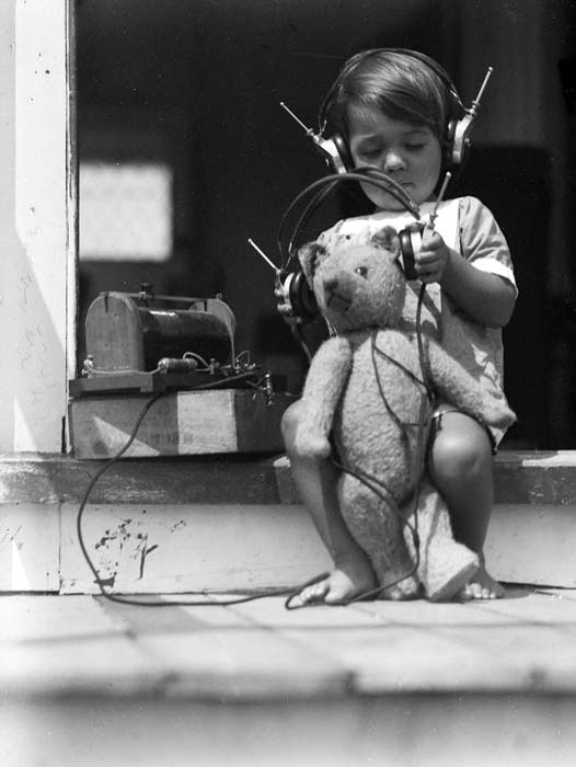 Boy and teddy bear listen to a crystal set, 1928