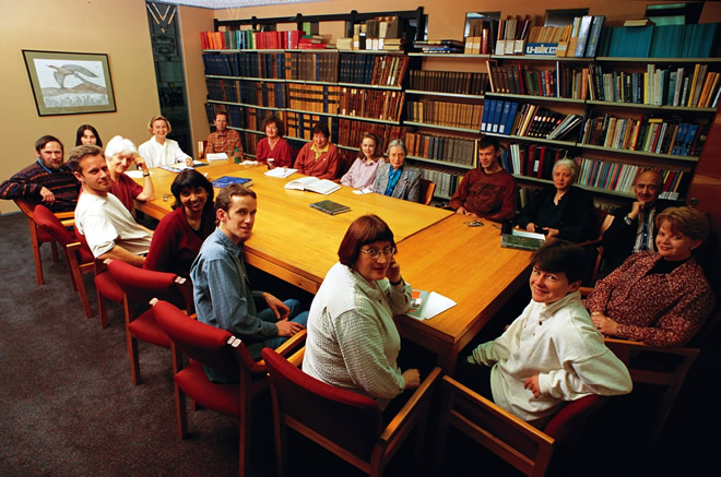 Staff around a table in a library looking up at camera