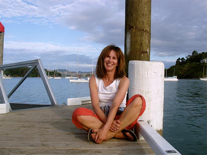 Woman sitting cross-legged on wharf smiling