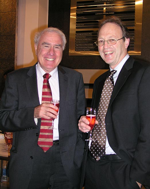 Two men in suits drinking wine and laughing 
