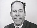 A head and shoulders portrait of a middle-aged man in a suit and tie