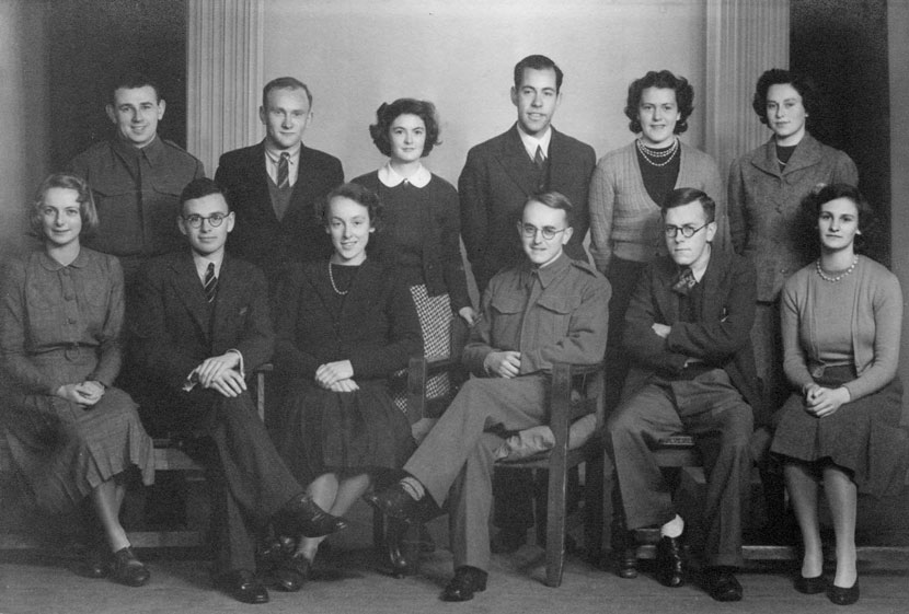 A formal portrait of a group of people, some standing and some seated. 