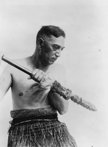 Peter Henry Buck in traditional Māori dress, holding a taiaha