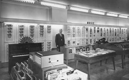 Walter James Sinton behind the counter at Charles Begg and Company's music store, Dunedin, 1970s