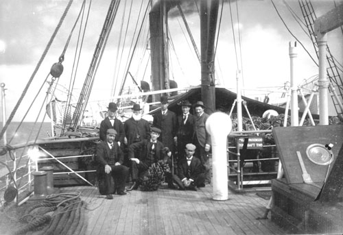A group of well-dressed men aboard a steamship. 