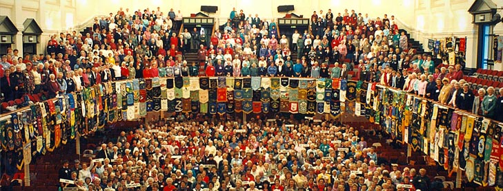 Large group in hall with sewn banners hanging off the upstairs balcony