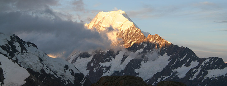 Snow-capped mountain peal poking through clouds