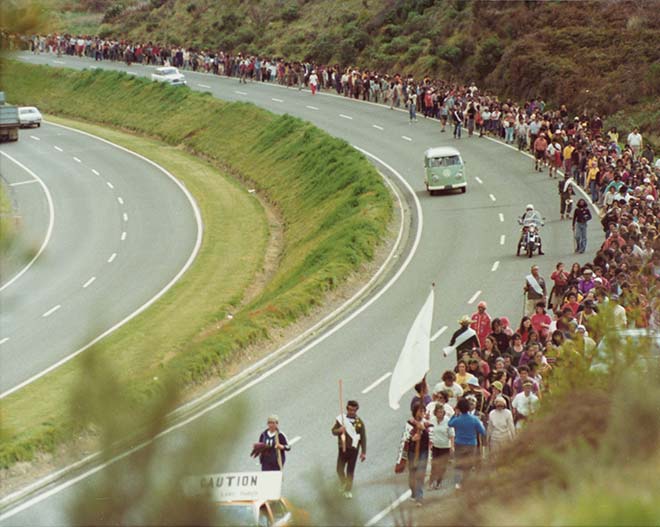 Hundreds of people walk alongside a motorway