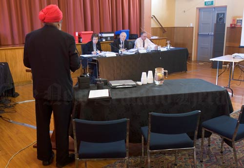 Man speaking in front of commissioners seated behind a desk 