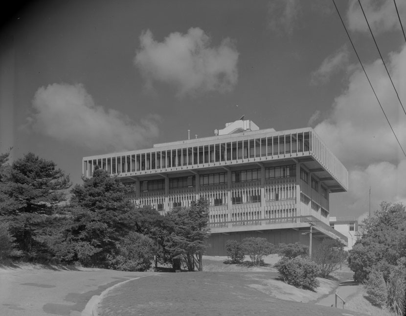 A five storey building surrounded by lawns and trees.