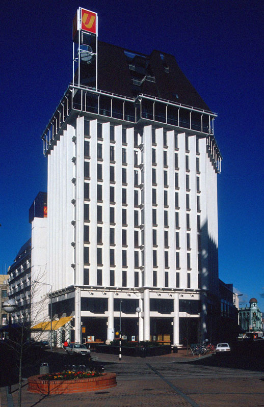 A tall, white multi-level building in a city street.