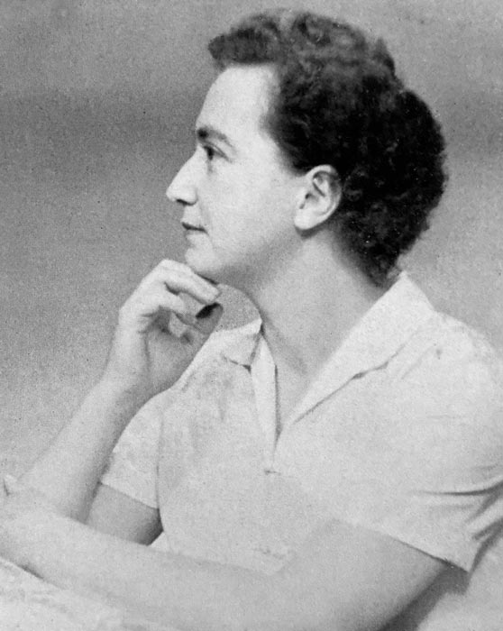 A black and white studio portrait of Ruth Dallas, seated in profile with her head resting on her hand.