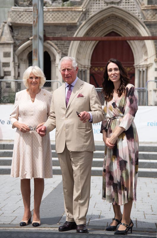 Prince of Wales stands between his wife, the Duchess of Cornwall, and New Zealand Prime Minister Jacinda Ardern on steps outside the Christchurch Cathedral.
