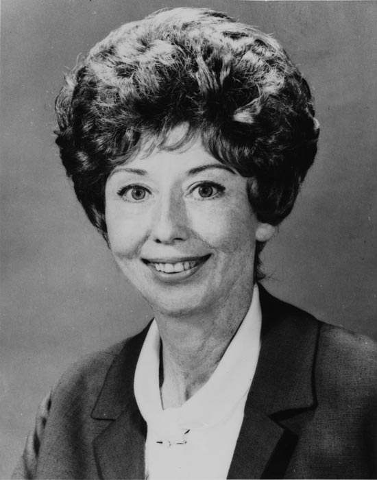 A head and shoulders portrait of a smiling Jean Wishart with elegantly styled hair.