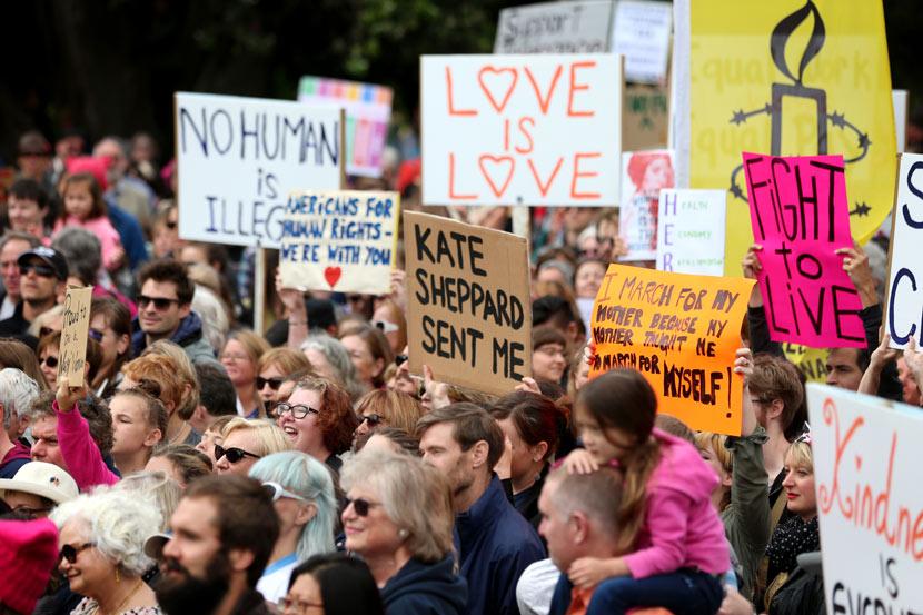Crowd holding various placards and signs.